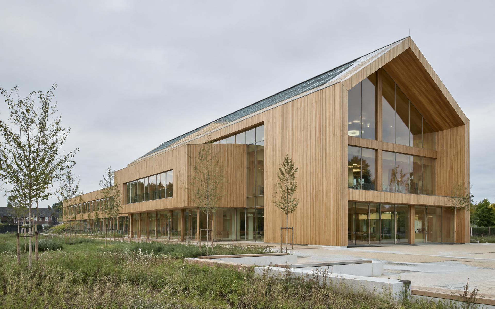 Houten gebouw met verticale gevelbekleding en grote glaspartijen bij daglicht